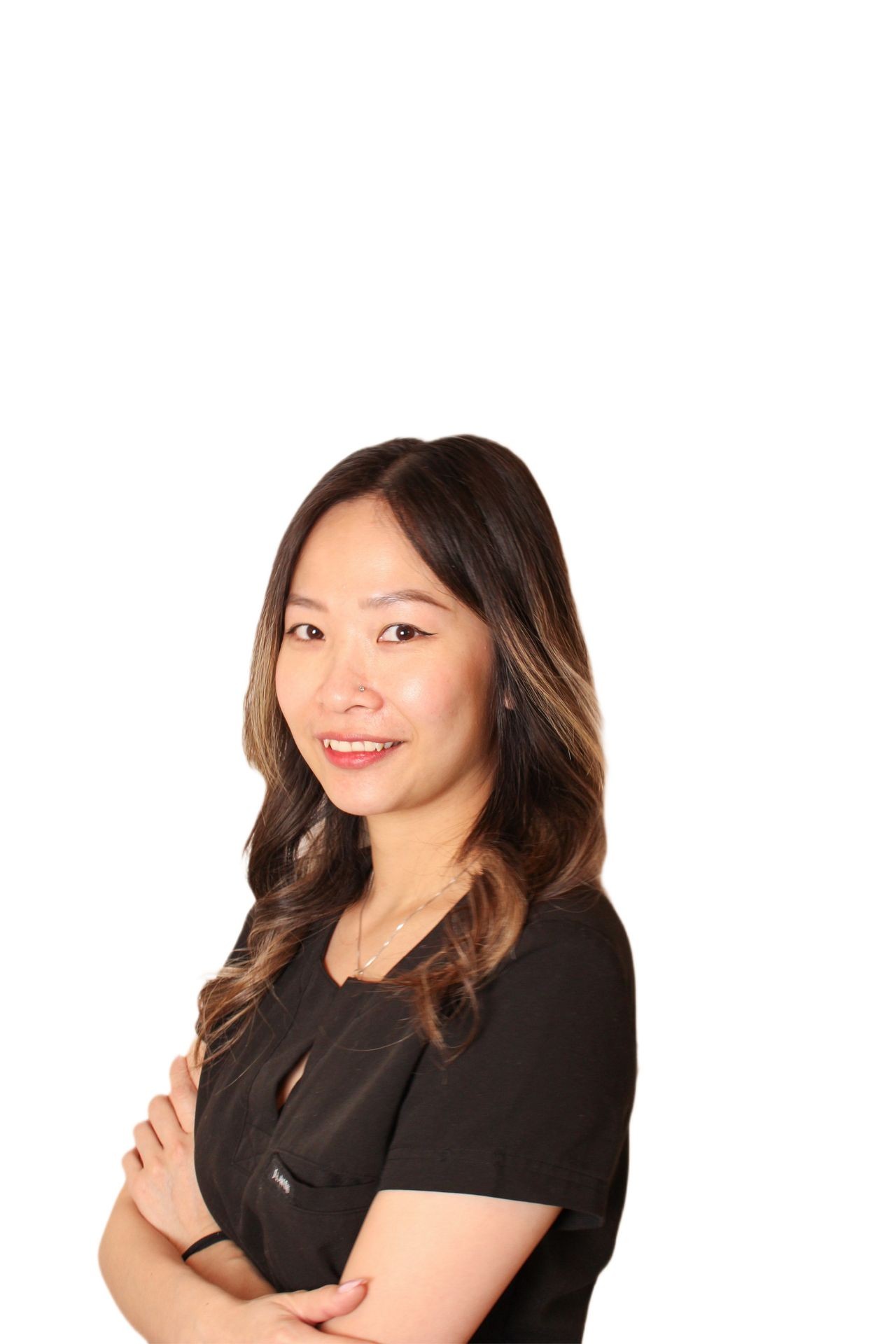 Woman with crossed arms, wearing a black outfit, smiling, and standing against a white background.